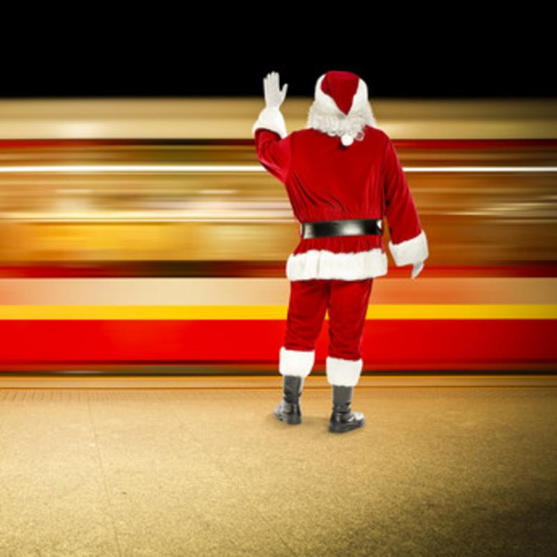 Julemand med armen strakt ser bekymret et tog køre forbi.